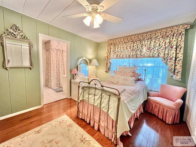 1914 S Parkwood Dr, Harlingen, TX 78550 - bedroom with wood finished floors, ceiling fan, a decorative wall, and connected bathroom