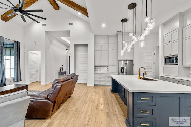 kitchen with sink, beamed ceiling, light hardwood / wood-style floors, pendant lighting, and appliances with stainless steel finishes