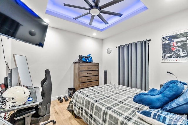 bedroom featuring ceiling fan, wood-type flooring, and a tray ceiling