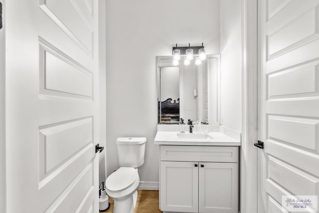 bathroom with hardwood / wood-style flooring, vanity, and toilet