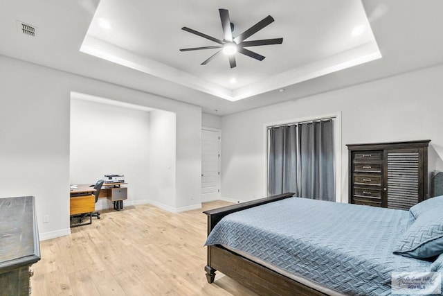 bedroom with a raised ceiling, light hardwood / wood-style flooring, and ceiling fan