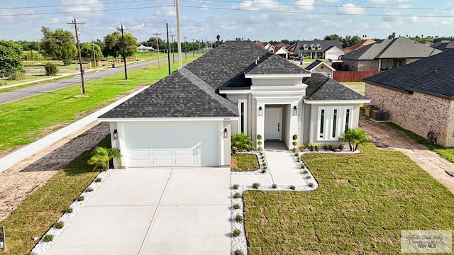 view of front of house featuring a garage, a front lawn, and central air condition unit