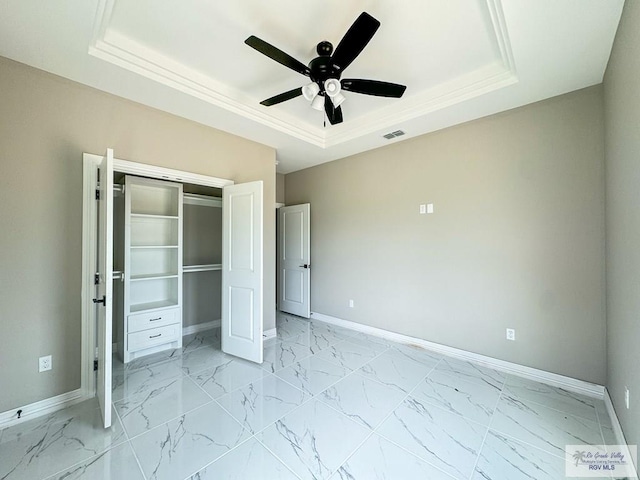 unfurnished bedroom with ceiling fan, a closet, and a tray ceiling