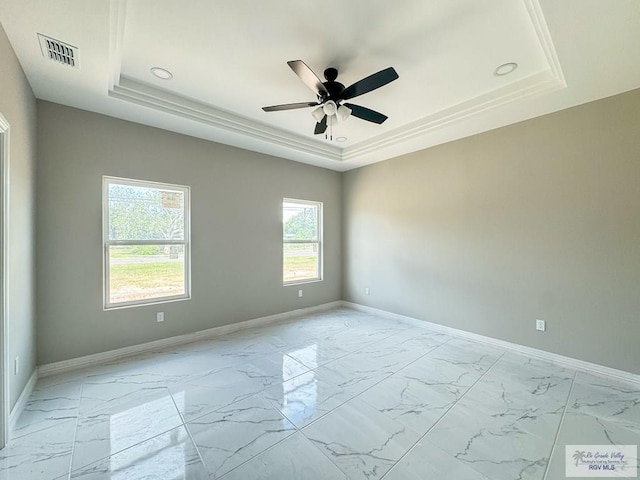 empty room featuring ceiling fan and a raised ceiling