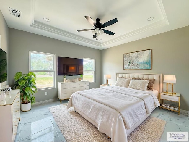 bedroom featuring ceiling fan, a raised ceiling, and multiple windows