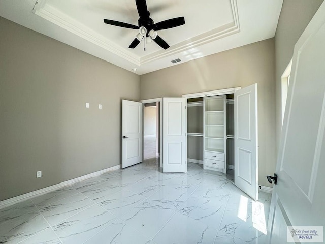 unfurnished bedroom with a tray ceiling, ceiling fan, and a closet