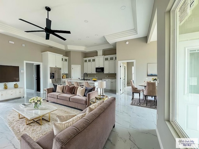 living room featuring ceiling fan, crown molding, sink, and a high ceiling