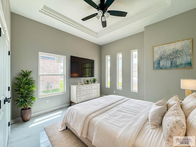 bedroom with ceiling fan and a raised ceiling