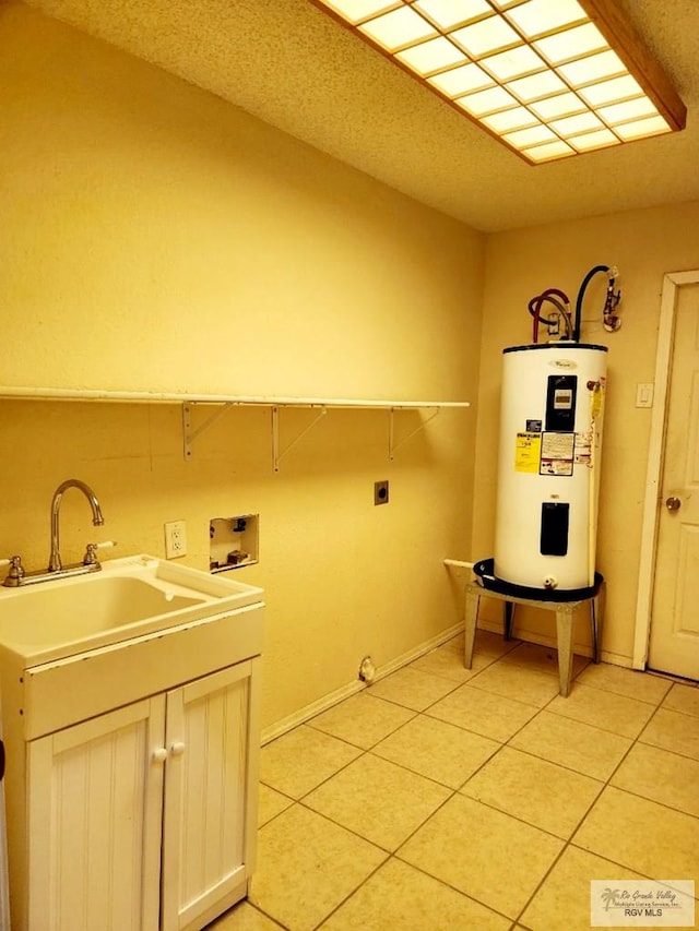 washroom featuring electric water heater, sink, light tile patterned floors, and hookup for an electric dryer