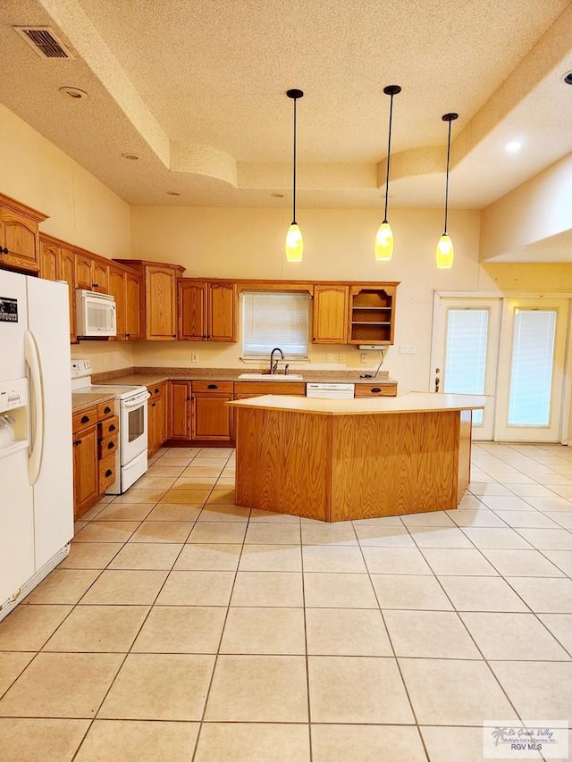 kitchen with a center island, white appliances, hanging light fixtures, and a tray ceiling