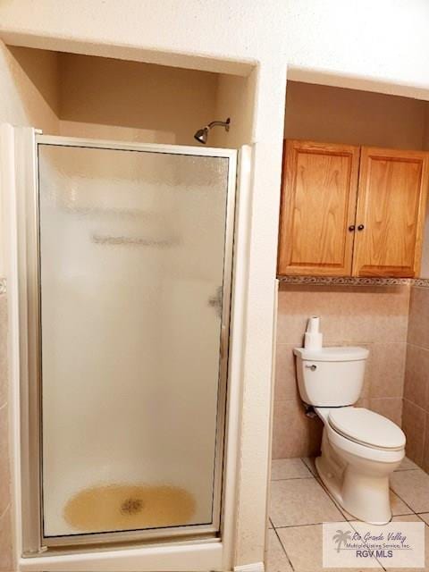 bathroom featuring tile patterned floors, tile walls, an enclosed shower, and toilet