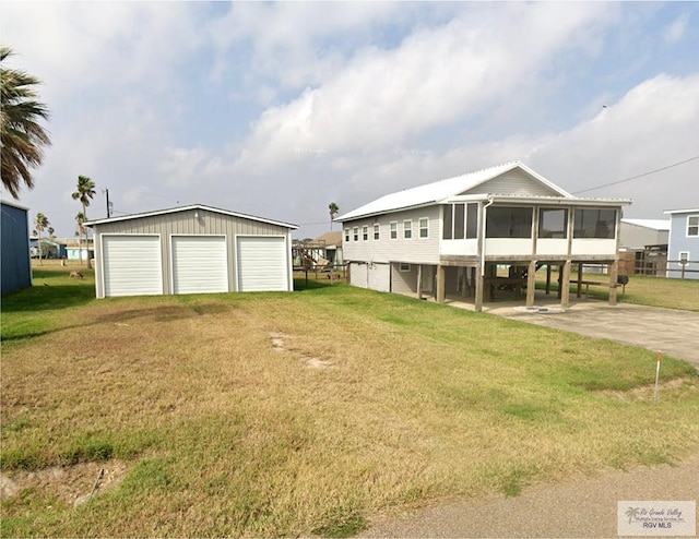 view of front of property with a sunroom, a detached garage, and a front yard