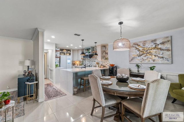 tiled dining room with ornamental molding and sink