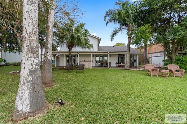 rear view of property featuring a lawn and a patio