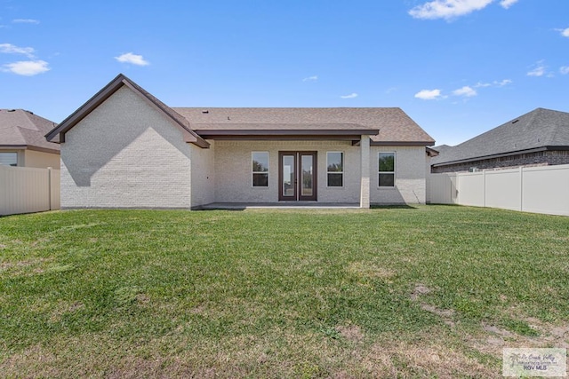 rear view of property with brick siding, french doors, a lawn, and a fenced backyard