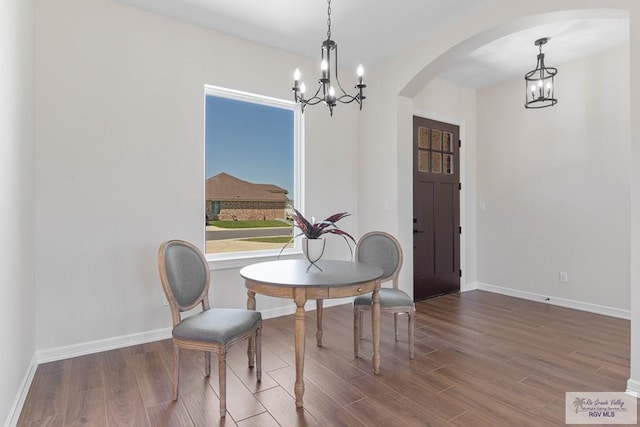 dining room featuring baseboards, arched walkways, a notable chandelier, and wood finished floors