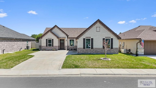 view of front of home featuring a front lawn, fence, a shingled roof, brick siding, and central AC unit