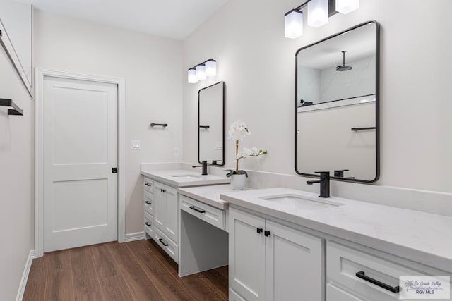 full bath featuring a sink, baseboards, wood finished floors, and double vanity