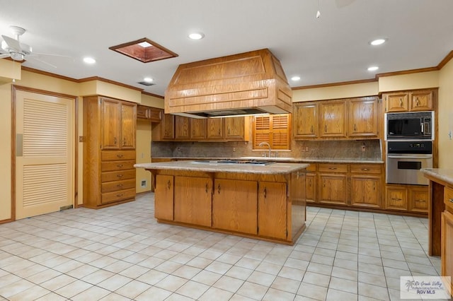 kitchen with black microwave, custom exhaust hood, a center island, and stainless steel oven