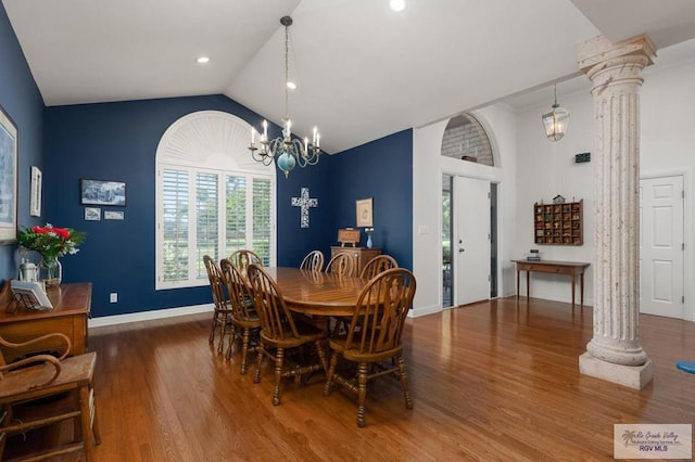 dining area with ornate columns, a chandelier, wood-type flooring, and vaulted ceiling