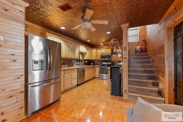 kitchen featuring ceiling fan, stainless steel appliances, wooden walls, pendant lighting, and decorative backsplash