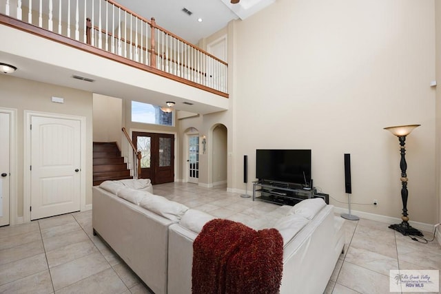 living room featuring french doors, light tile patterned floors, and a high ceiling