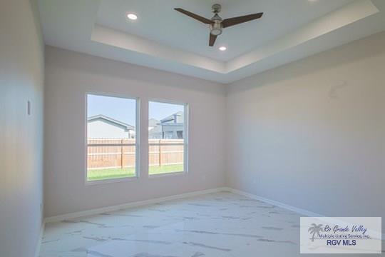 spare room with a raised ceiling and ceiling fan