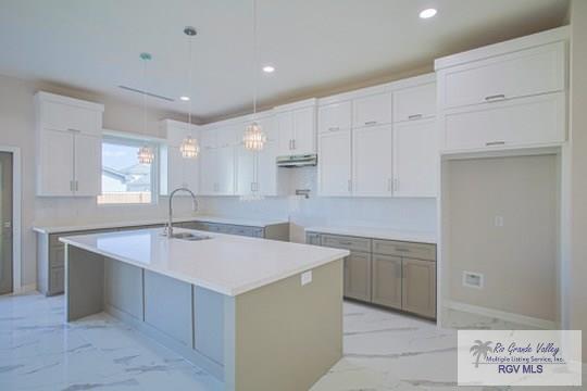 kitchen with white cabinets, sink, a center island with sink, and hanging light fixtures