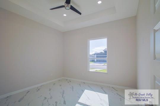 spare room featuring a raised ceiling and ceiling fan