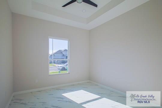 empty room with a raised ceiling and ceiling fan