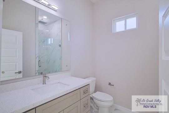 bathroom with a shower with door, vanity, and toilet