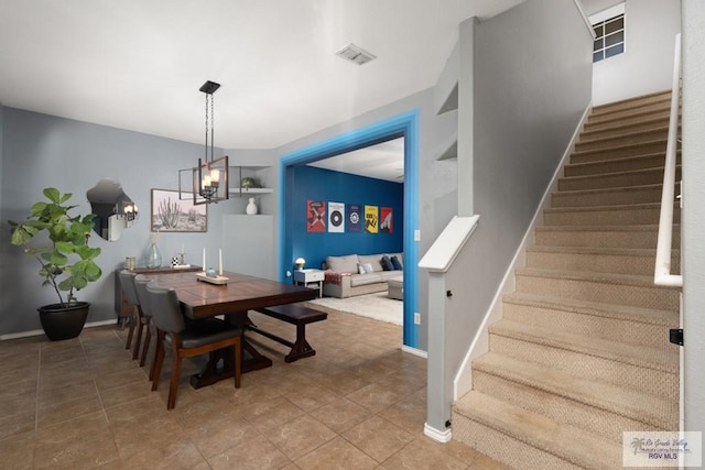 dining space with stairs, baseboards, visible vents, and a chandelier