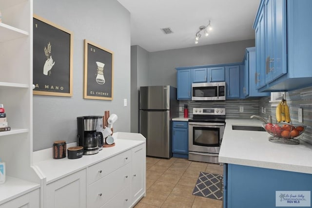 kitchen with visible vents, a sink, appliances with stainless steel finishes, blue cabinets, and backsplash