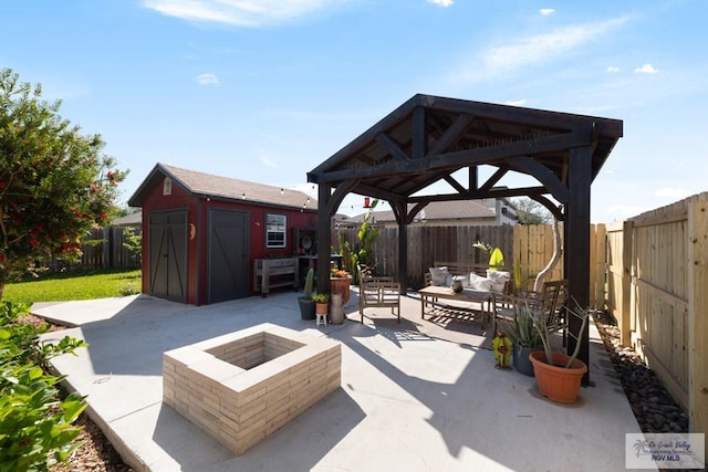 view of patio featuring a storage unit, an outbuilding, a fenced backyard, a gazebo, and an outdoor living space with a fire pit