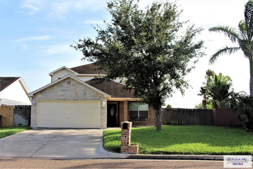 view of front facade featuring a front yard, driveway, an attached garage, and fence