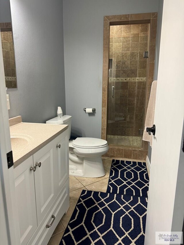 bathroom featuring tile patterned flooring, vanity, toilet, and walk in shower