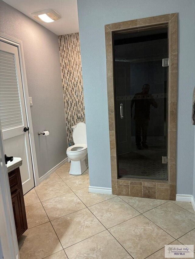 bathroom featuring tile patterned floors, vanity, toilet, and a shower with shower door