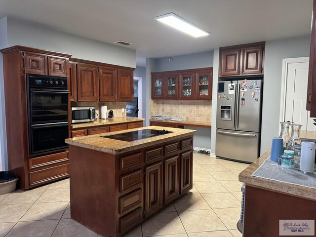 kitchen with tasteful backsplash, dark brown cabinets, black appliances, light tile patterned floors, and a center island