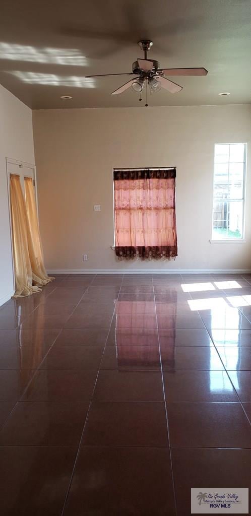 spare room featuring ceiling fan and dark tile patterned flooring