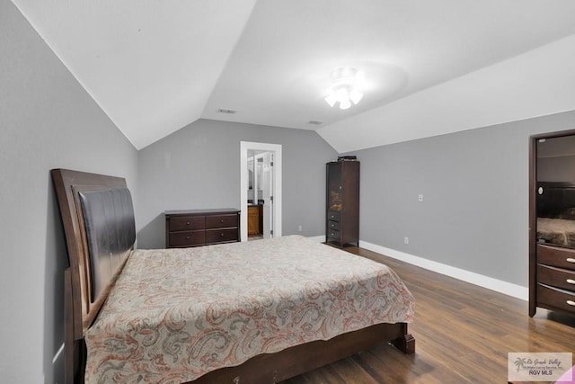 bedroom featuring dark wood-style flooring, vaulted ceiling, and baseboards