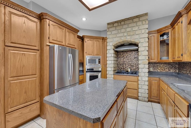 kitchen with tasteful backsplash, a kitchen island, glass insert cabinets, stainless steel appliances, and light tile patterned flooring