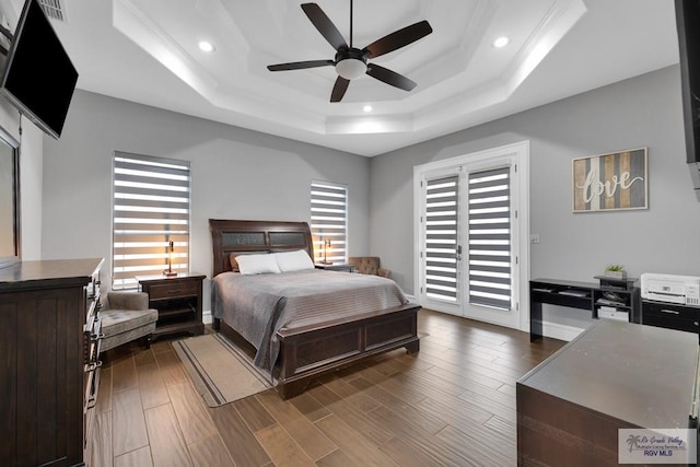 bedroom featuring access to exterior, a tray ceiling, dark wood finished floors, and recessed lighting