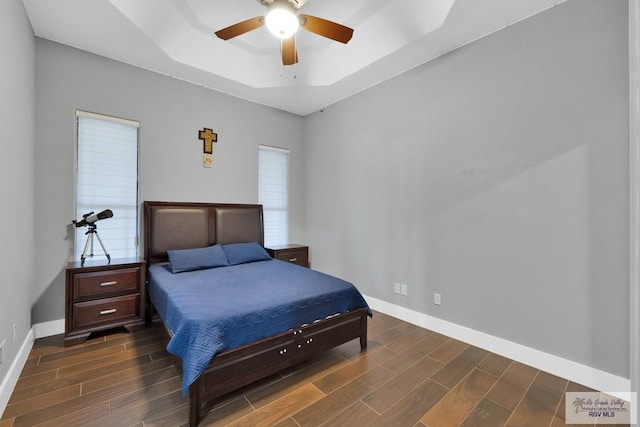 bedroom featuring baseboards, a tray ceiling, ceiling fan, and wood finish floors