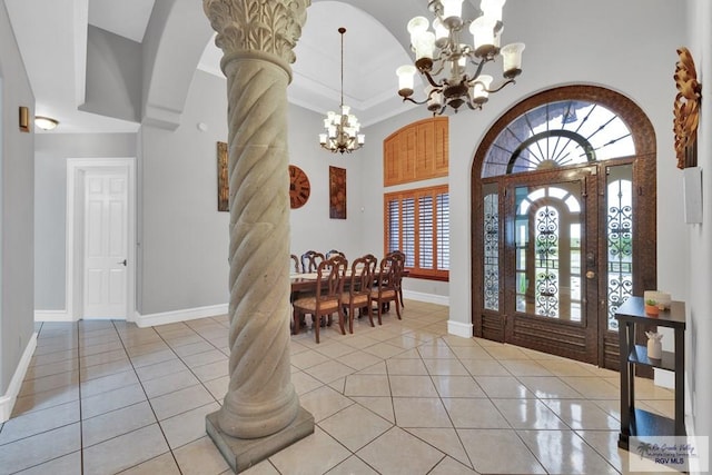 entrance foyer with light tile patterned floors, decorative columns, a chandelier, and arched walkways