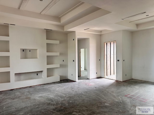 unfurnished living room with a tray ceiling and built in shelves