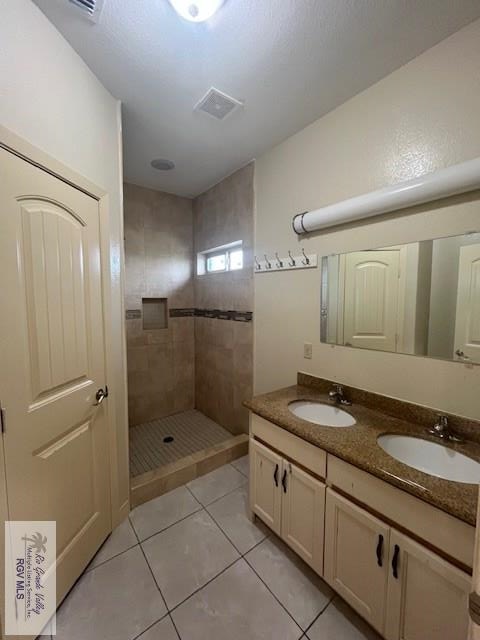 bathroom with vanity, tiled shower, and tile patterned floors