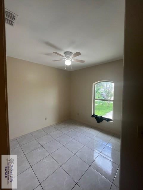 tiled spare room with ceiling fan