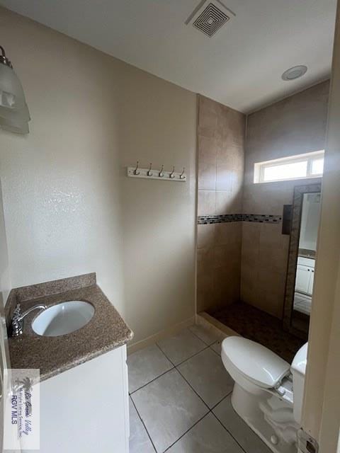 bathroom featuring vanity, toilet, tile patterned flooring, and a tile shower