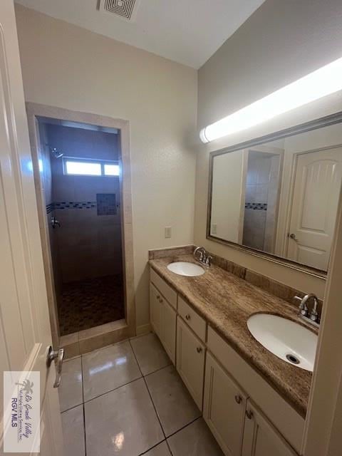 bathroom featuring a tile shower, vanity, and tile patterned floors