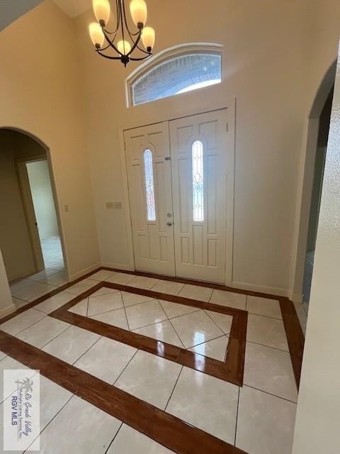 entrance foyer with light tile patterned floors, a chandelier, and a high ceiling